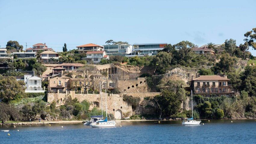 sailing boats on Swan River in front of cliffside with residential housing